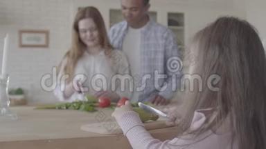在现代厨房里，一位<strong>非洲裔美国</strong>人和一位微笑的美女站在桌边做沙拉。<strong>小女孩</strong>